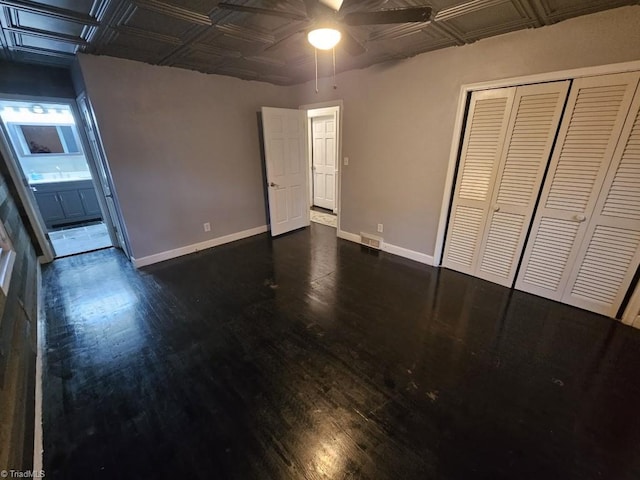 unfurnished bedroom with ceiling fan, dark hardwood / wood-style floors, and a closet