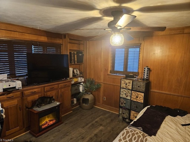 interior space featuring a textured ceiling, dark hardwood / wood-style flooring, wooden walls, and ceiling fan