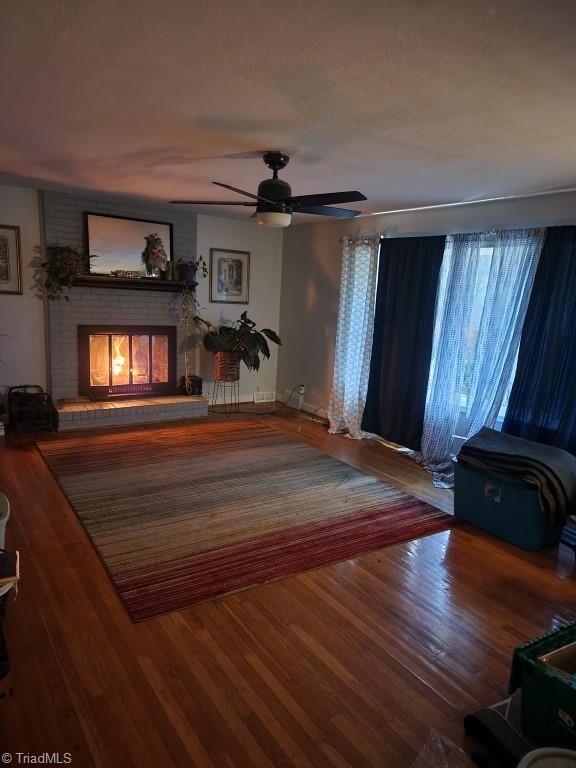 living room with hardwood / wood-style floors, a fireplace, and ceiling fan