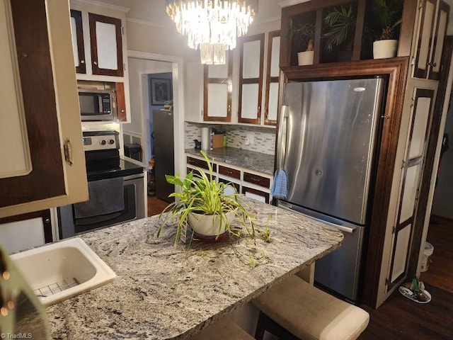 kitchen featuring stainless steel appliances, dark hardwood / wood-style flooring, a kitchen breakfast bar, backsplash, and pendant lighting