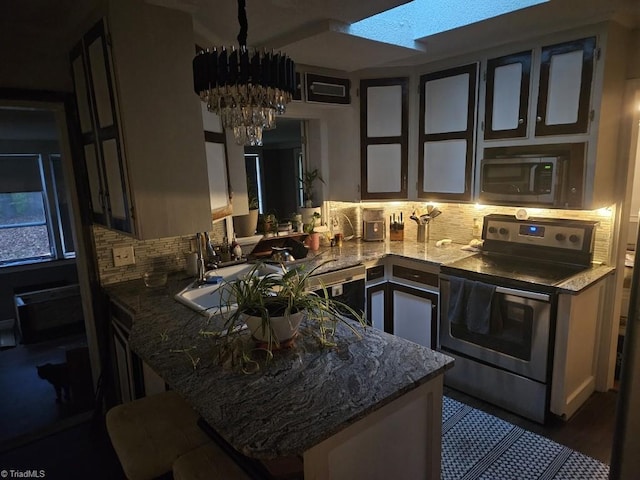 kitchen featuring kitchen peninsula, stone countertops, backsplash, and appliances with stainless steel finishes