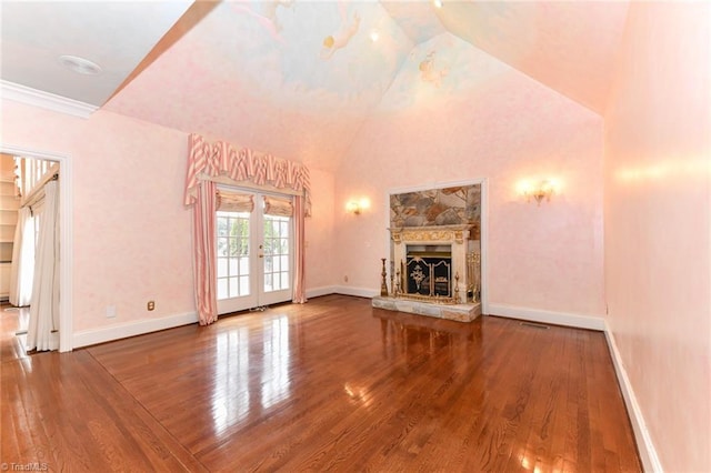 unfurnished living room featuring lofted ceiling, crown molding, wood-type flooring, a stone fireplace, and french doors