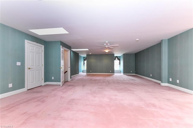 carpeted spare room with ceiling fan and a skylight