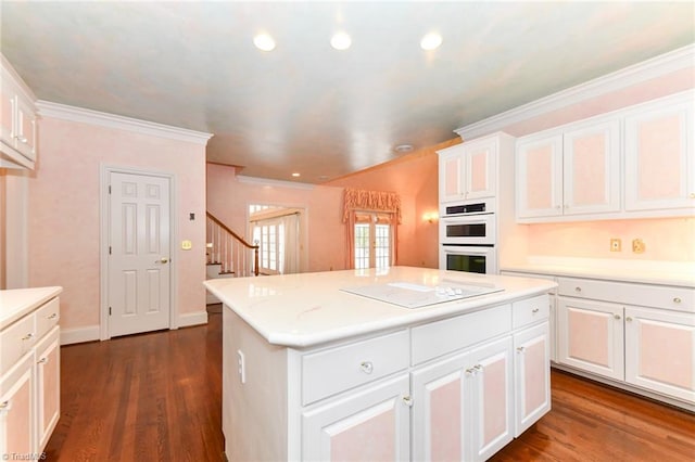 kitchen featuring dark wood-type flooring, white cabinetry, electric cooktop, a center island, and double oven