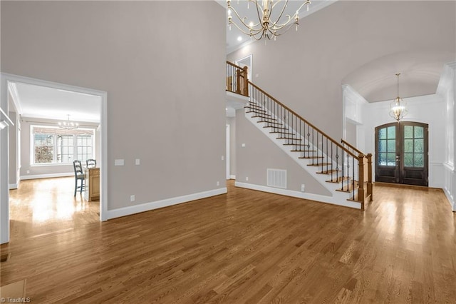 foyer entrance with a chandelier, french doors, wood finished floors, and stairs