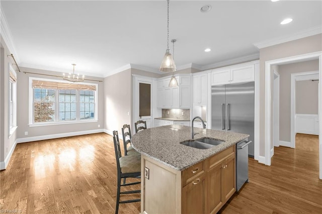 kitchen featuring appliances with stainless steel finishes, ornamental molding, a sink, and wood finished floors