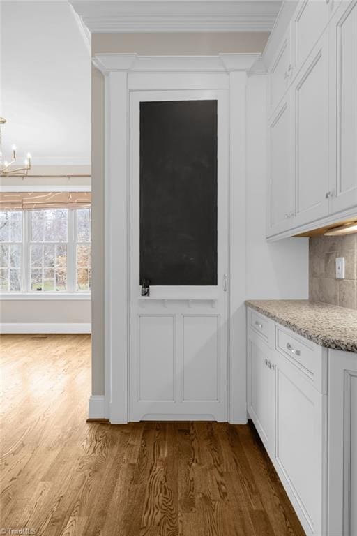 kitchen featuring dark wood-style floors, white cabinetry, ornamental molding, and tasteful backsplash