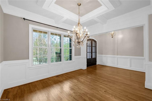 unfurnished dining area with coffered ceiling, wood finished floors, beamed ceiling, an inviting chandelier, and crown molding