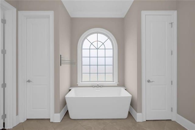 full bathroom with baseboards, ornamental molding, a soaking tub, and tile patterned floors