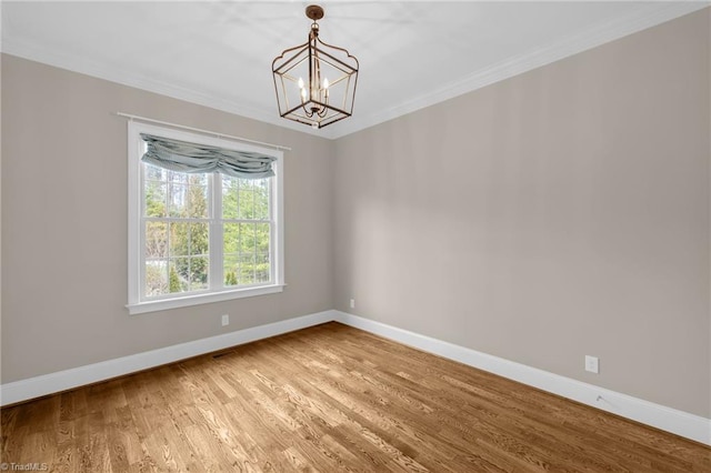 empty room featuring ornamental molding, baseboards, light wood finished floors, and an inviting chandelier