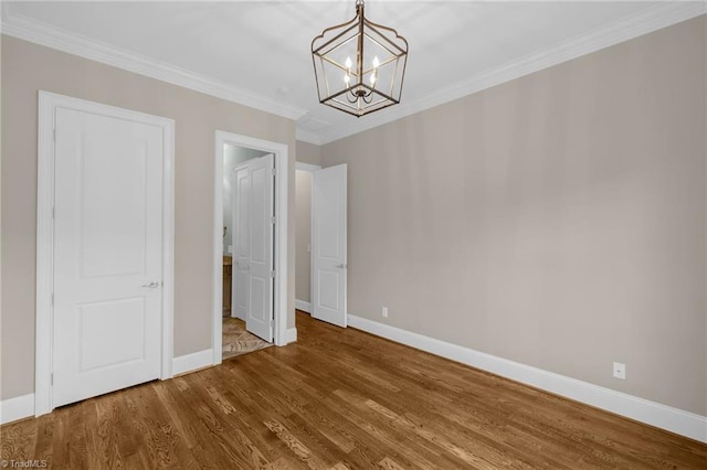 interior space with an inviting chandelier, baseboards, ornamental molding, and wood finished floors