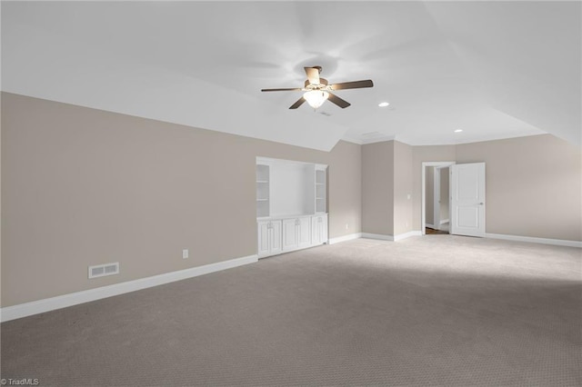 empty room with lofted ceiling, ceiling fan, built in shelves, visible vents, and baseboards