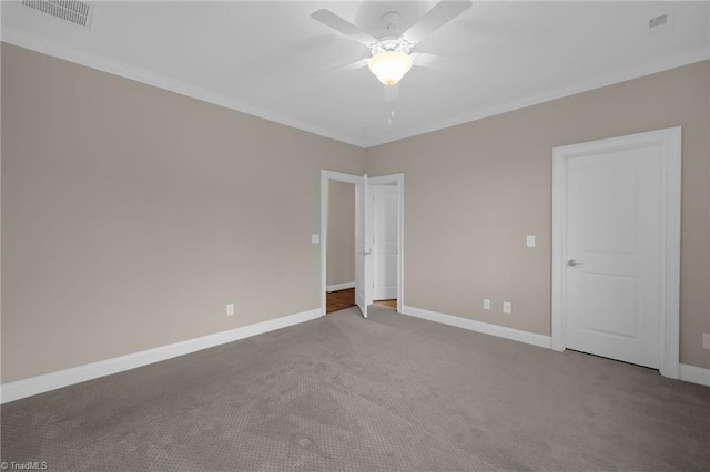 carpeted empty room featuring visible vents, crown molding, baseboards, and a ceiling fan