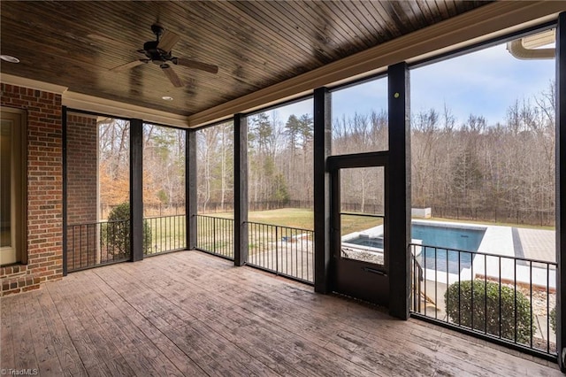 unfurnished sunroom with wooden ceiling, a healthy amount of sunlight, and a forest view