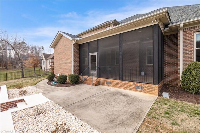 back of house featuring brick siding, crawl space, fence, and a sunroom