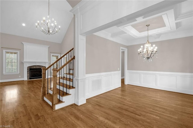 interior space with visible vents, a fireplace with flush hearth, wood finished floors, stairs, and a notable chandelier