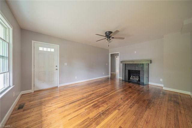 unfurnished living room featuring a brick fireplace, hardwood / wood-style floors, and ceiling fan