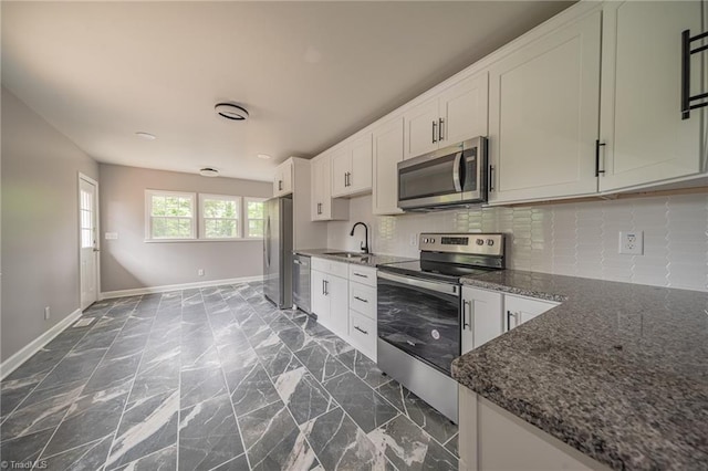 kitchen with sink, dark stone countertops, stainless steel appliances, white cabinets, and decorative backsplash