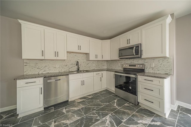 kitchen with white cabinetry, sink, backsplash, dark stone counters, and stainless steel appliances