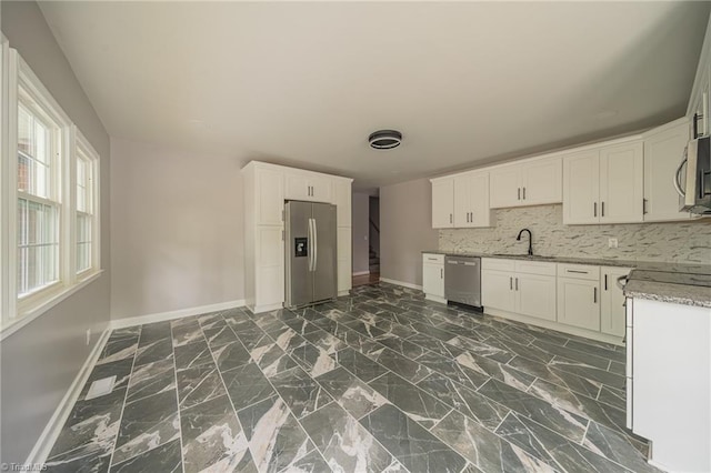 kitchen featuring sink, appliances with stainless steel finishes, light stone counters, white cabinets, and decorative backsplash