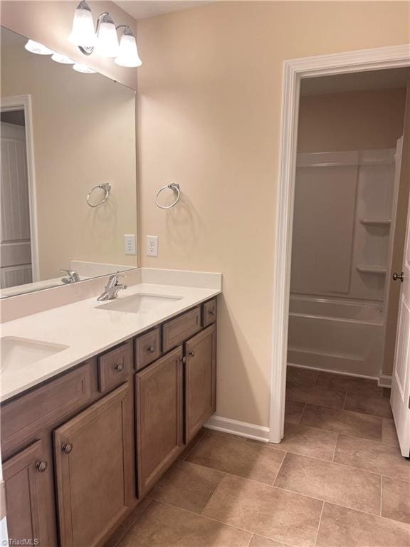 full bathroom featuring double vanity, baseboards, and a sink