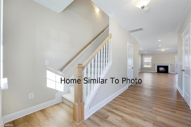 staircase with baseboards, ornamental molding, and wood finished floors