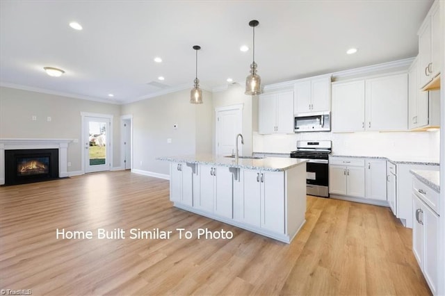 kitchen featuring stainless steel appliances, a sink, a kitchen island with sink, and white cabinets