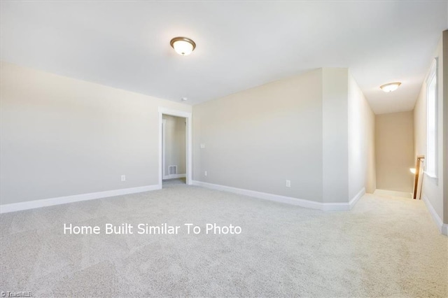 spare room with baseboards, visible vents, and light colored carpet