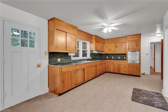 kitchen featuring ceiling fan, sink, stainless steel oven, and decorative backsplash