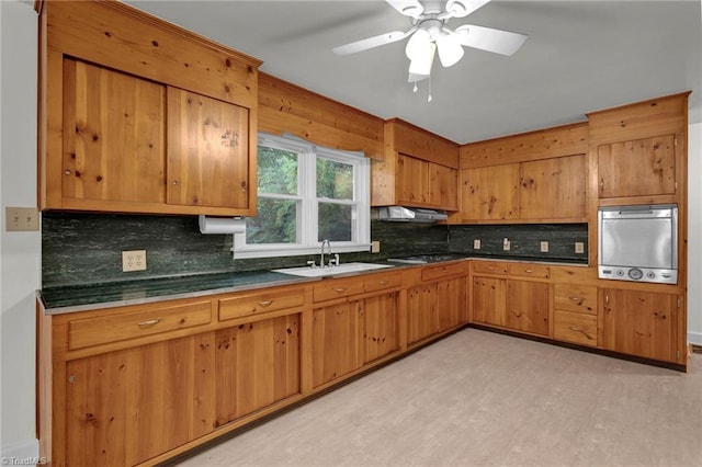 kitchen with ceiling fan, sink, exhaust hood, appliances with stainless steel finishes, and decorative backsplash