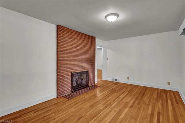 unfurnished living room with a brick fireplace and wood-type flooring