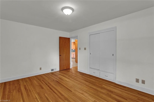 unfurnished bedroom with light wood-type flooring and a closet