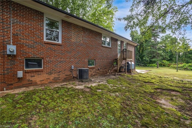 view of property exterior with central AC unit and a yard