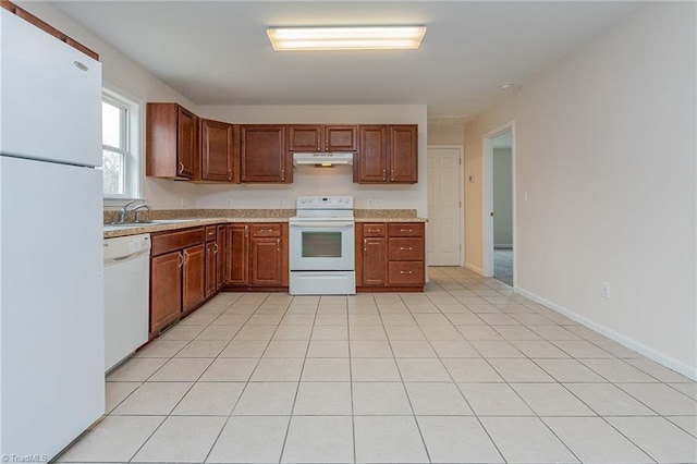 kitchen with baseboards, under cabinet range hood, light countertops, white appliances, and a sink