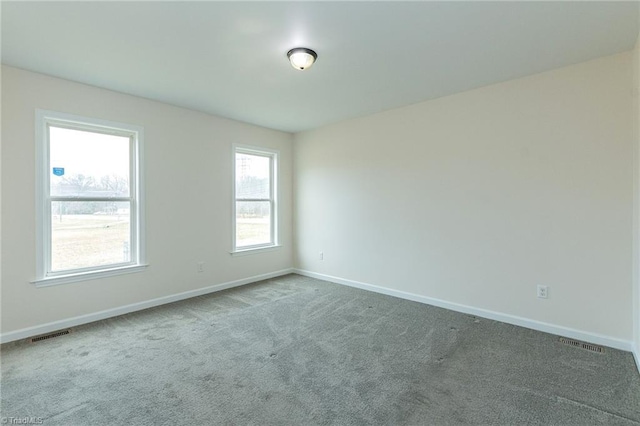 carpeted spare room featuring visible vents and baseboards