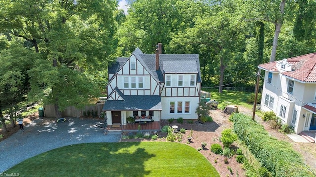 1501 Wiltshire St, High Point, NC 27265 - tudor-style house featuring a chimney, a wooded view, a front lawn, and a porch