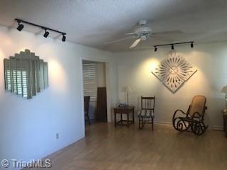 empty room with ceiling fan, rail lighting, and hardwood / wood-style flooring