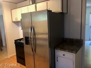 kitchen featuring white cabinets, dark stone countertops, stainless steel fridge with ice dispenser, and light hardwood / wood-style flooring