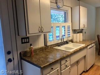 kitchen featuring white cabinets, dishwasher, light wood-type flooring, and sink