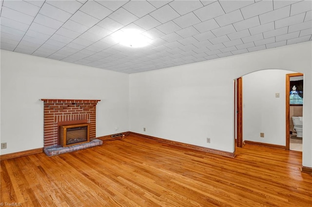 unfurnished living room featuring light hardwood / wood-style floors and a brick fireplace