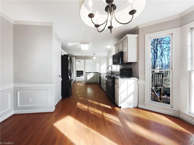 kitchen with black appliances, dark hardwood / wood-style flooring, white cabinets, ornamental molding, and sink