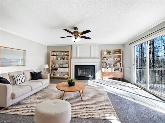 living room featuring a textured ceiling, ceiling fan, ornamental molding, and a fireplace