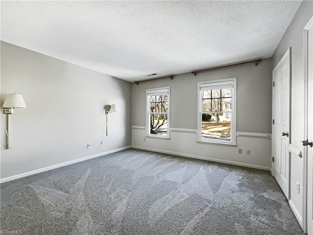 unfurnished room featuring dark carpet and a textured ceiling