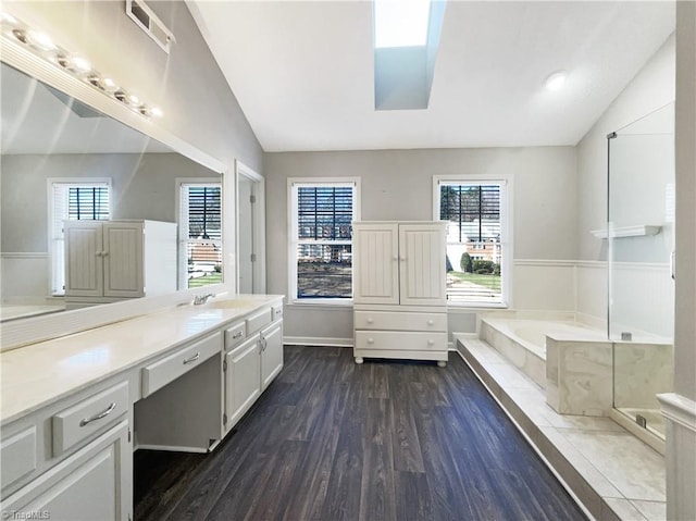 bathroom with lofted ceiling with skylight, vanity, a bathtub, and wood-type flooring