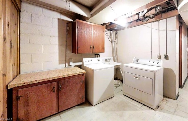 laundry room featuring washer and dryer, cabinet space, and concrete block wall