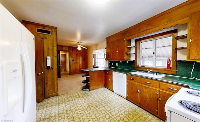 kitchen with light floors, visible vents, wood walls, a sink, and white appliances