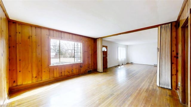 unfurnished room with visible vents, wood walls, and hardwood / wood-style floors