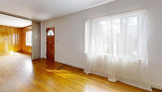 entrance foyer with hardwood / wood-style flooring, baseboards, and wood walls