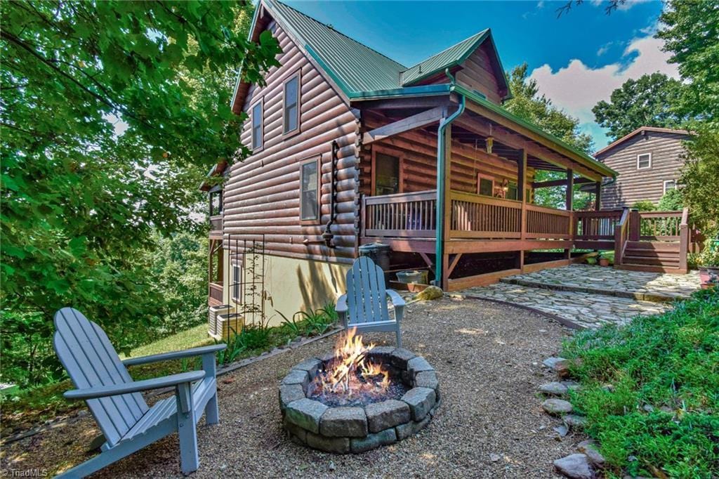 exterior space with metal roof, a fire pit, a wooden deck, and log siding