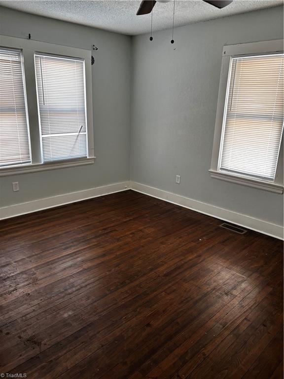 empty room with dark wood-type flooring, ceiling fan, and a textured ceiling